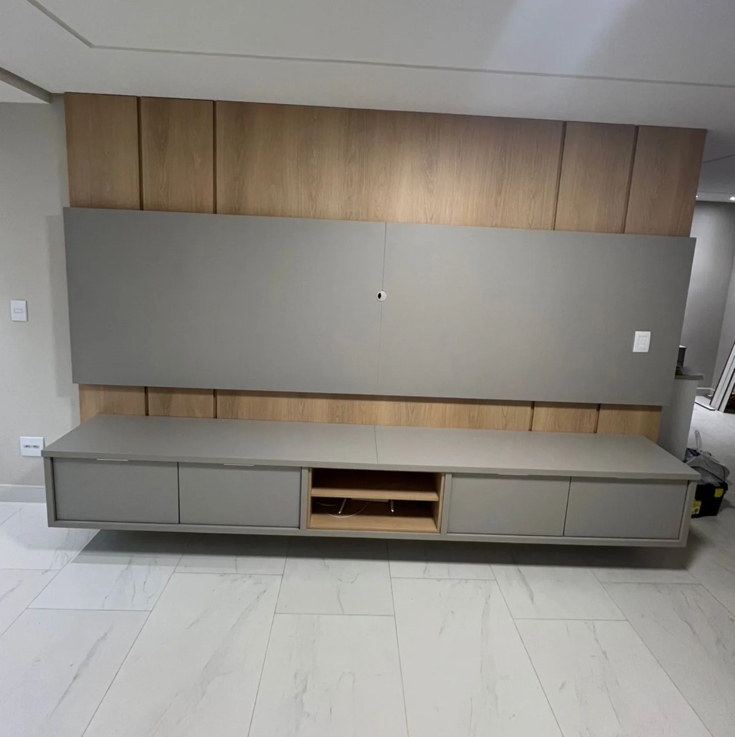 Painel de sala em madeira clara com rack suspenso planejado