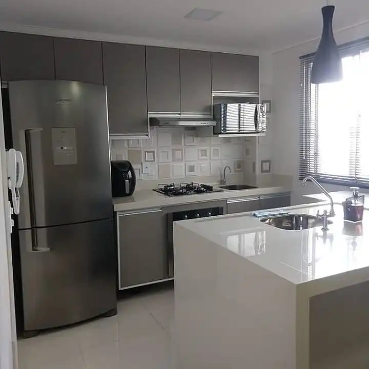 Cozinha planejada com armários cinza, ilha com cuba e cooktop