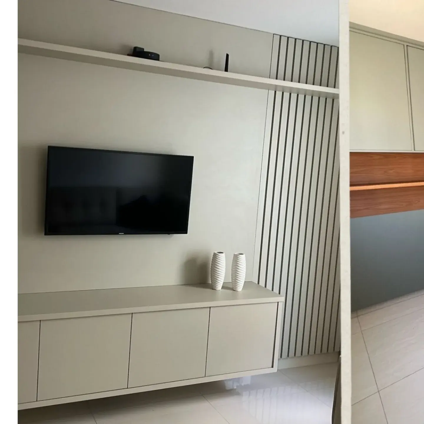 Sala com painel ripado, rack suspenso e prateleira sob medida